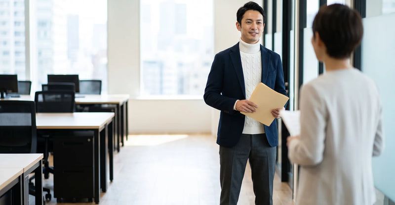 Man wearing a cream cable-knit turtleneck under a navy blazer in an office